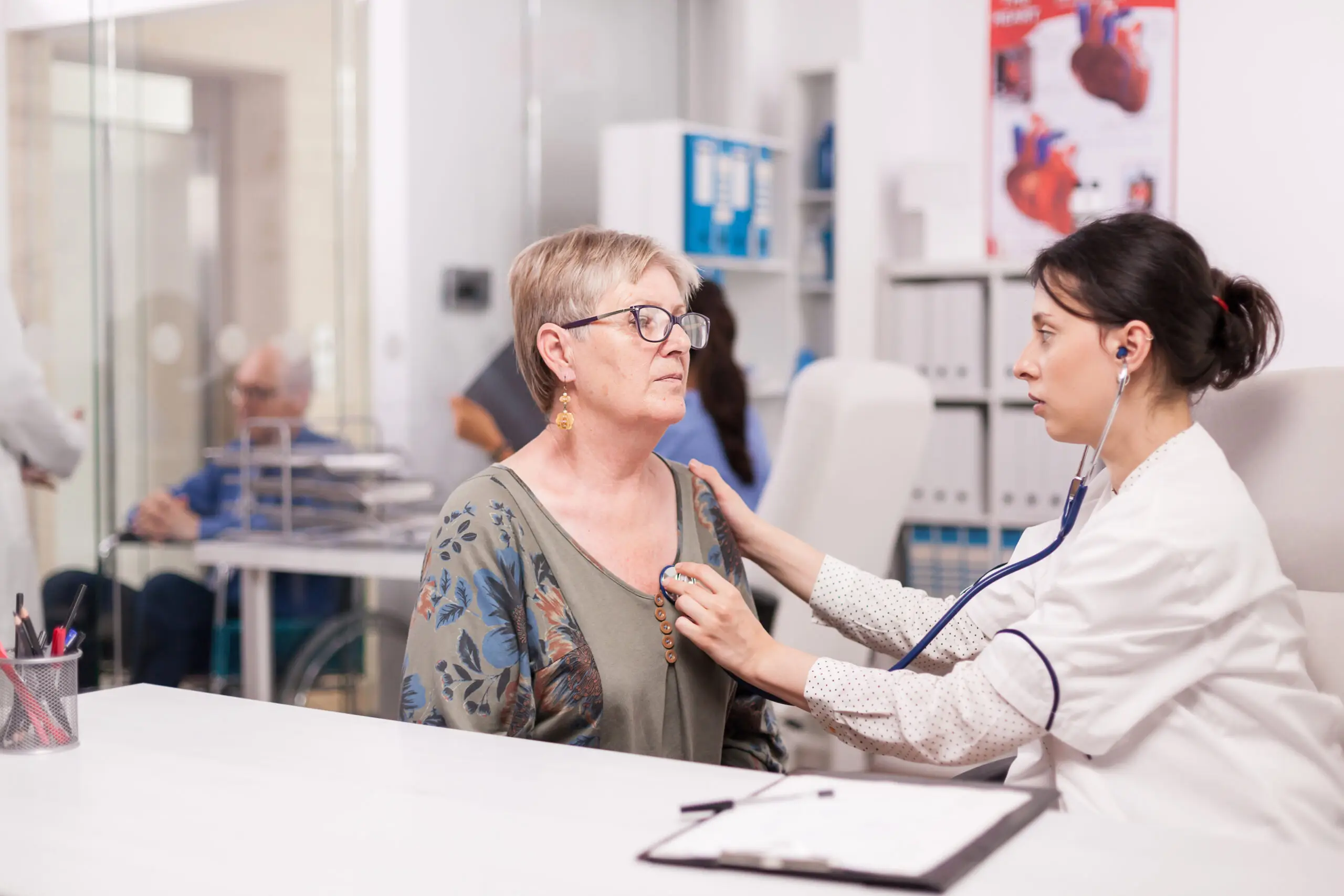 Doctor checking old woman heart beat
